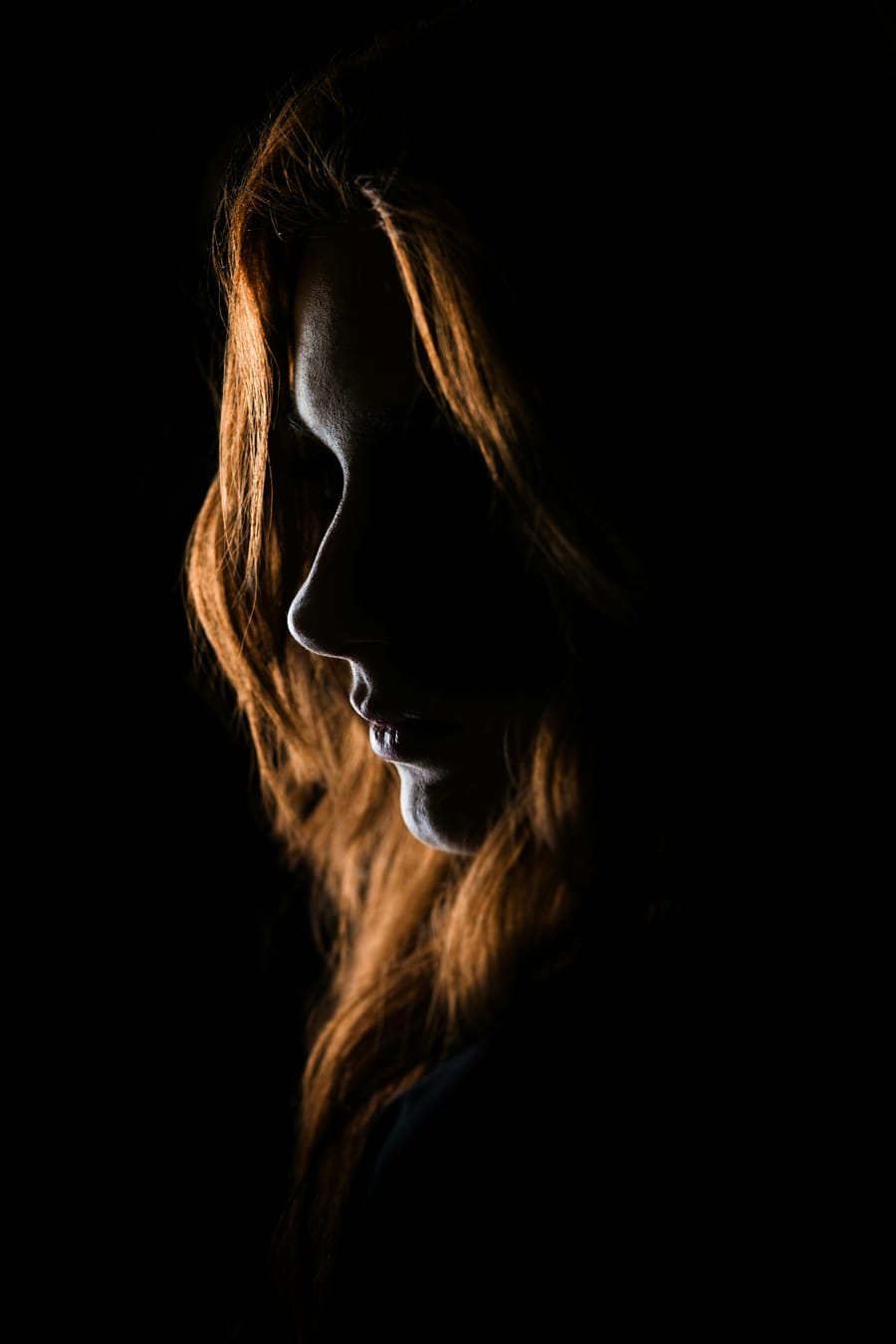 Un profil éclairé par une lumière rasante, dans la nuit.